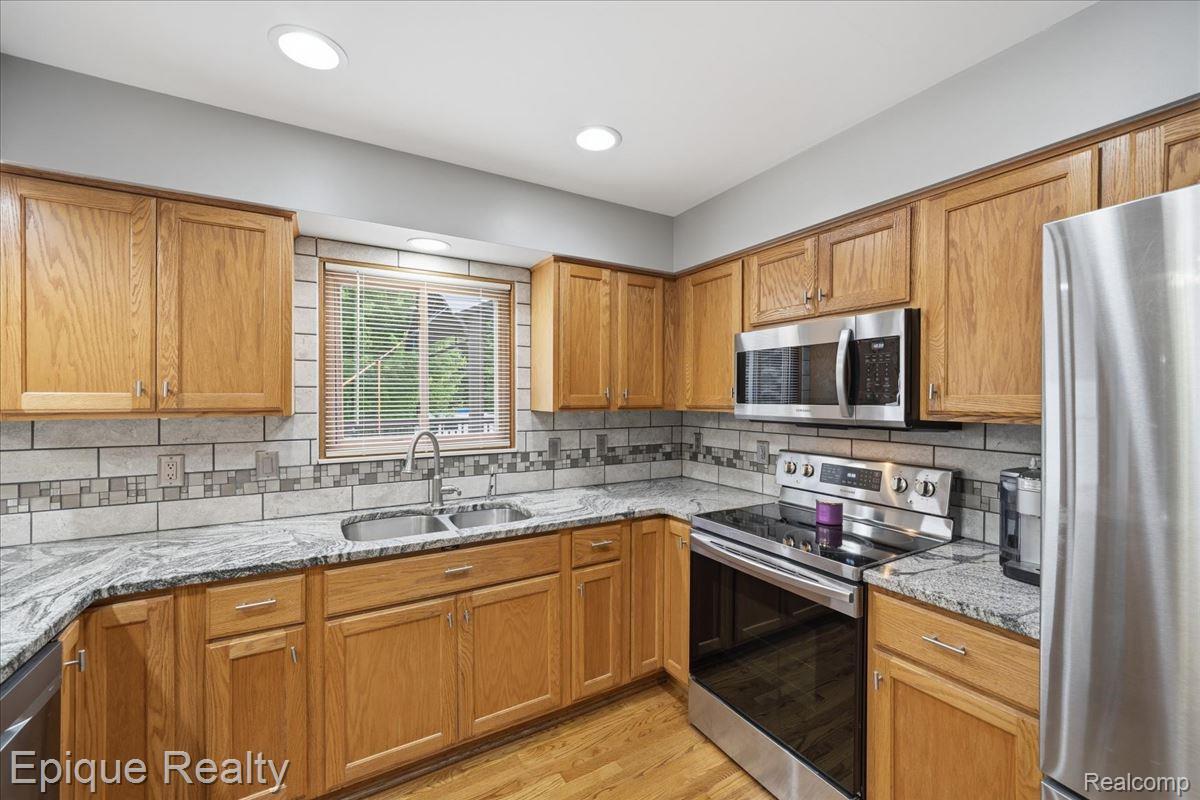 1221 Rhodes Road Lake Orion, MI 48360 - Photo 16 of 72 Kitchen featuring wood cabinetry, stainless steel appliances, speckled countertops, and a tiled backsplash