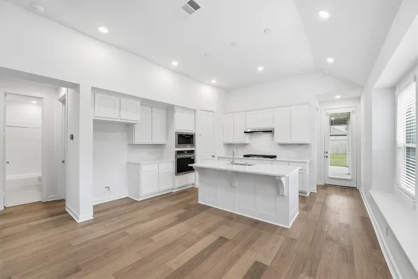 a large kitchen with a lot of counter space and wooden floor