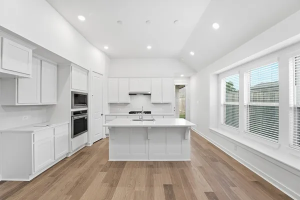 a view of a kitchen with kitchen island a sink wooden floor and a large window
