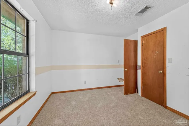 an empty room with windows and fan