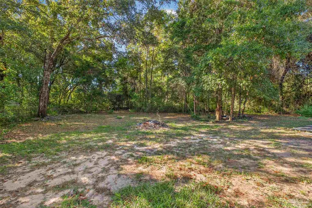 a backyard of a house with table and chairs under an umbrella