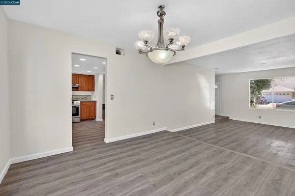 a view of an empty room with a kitchen and wooden floor