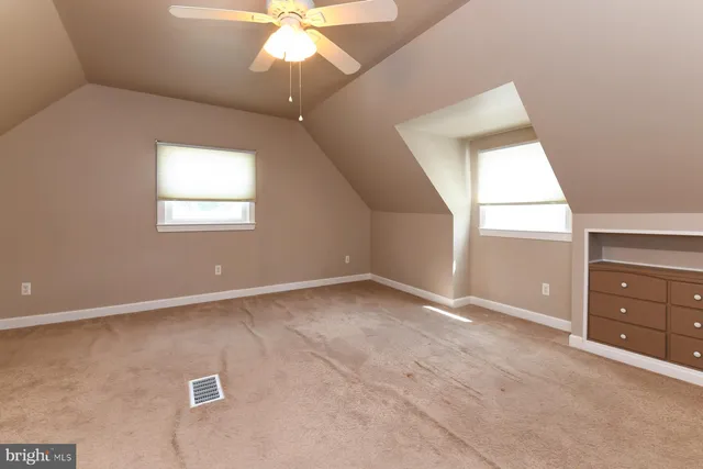 an empty room with a chandelier fan and windows