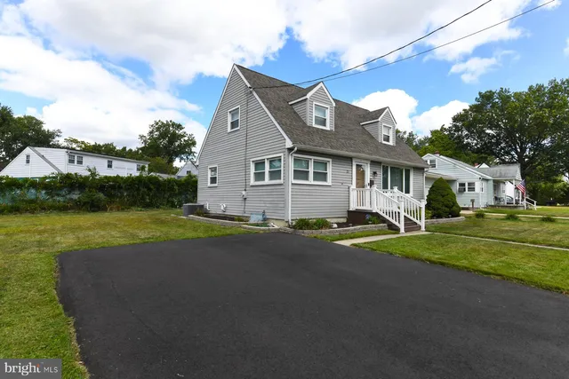 a view of a white house with a big yard and potted plants
