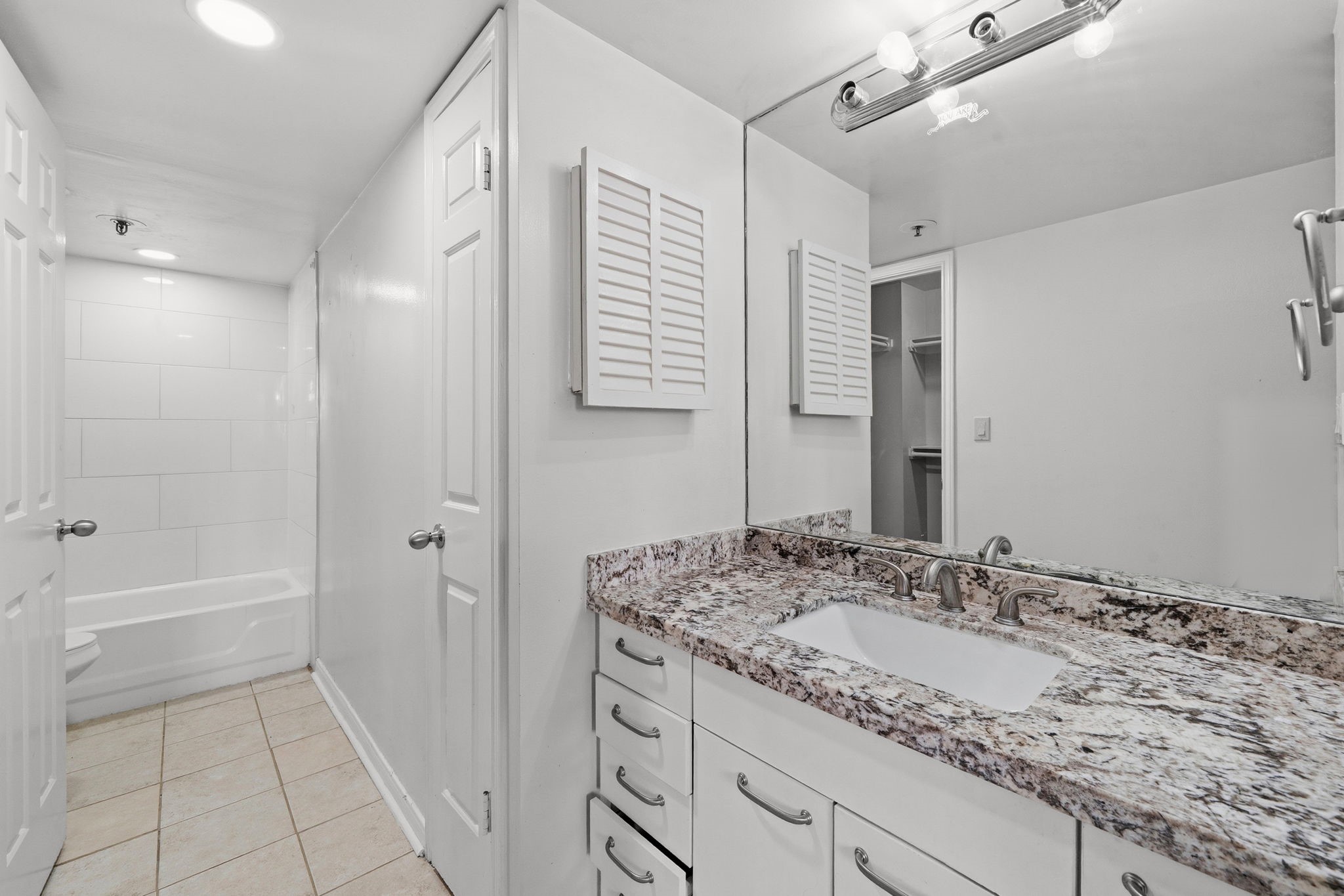 3525 Sage Road, Unit 504 Houston, TX 77056 - Photo 10 of 18 Beautiful bathroom featuring gorgeous granite countertops, large mirror, wooden cabinets, and a shower/tub combo.