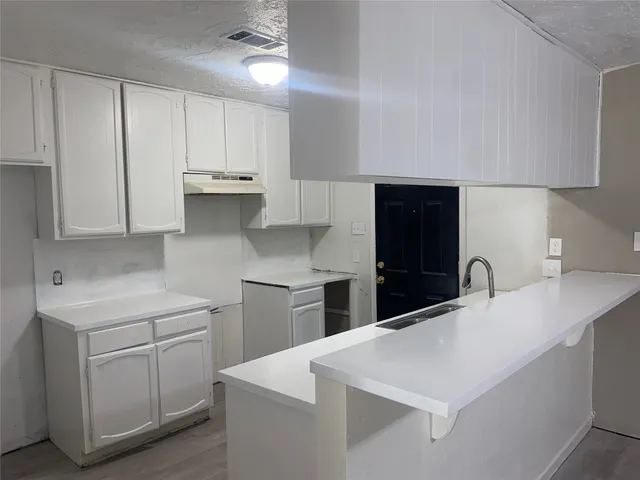a kitchen with white cabinets and sink