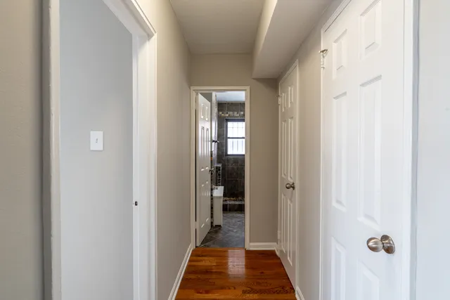a view of a hallway with wooden floor and a bathroom