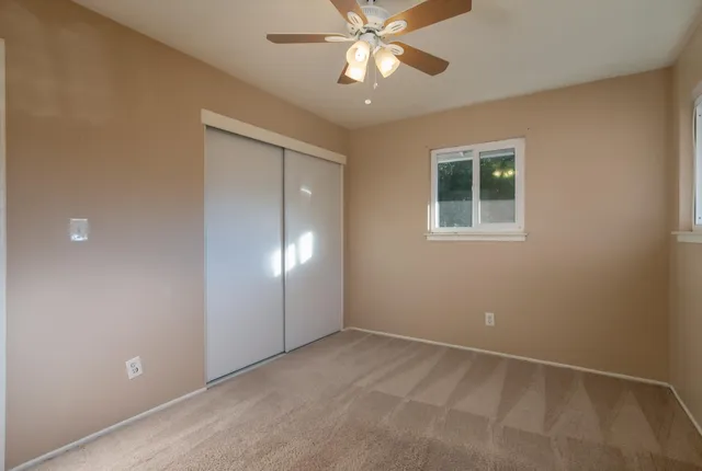 an empty room with windows and fan