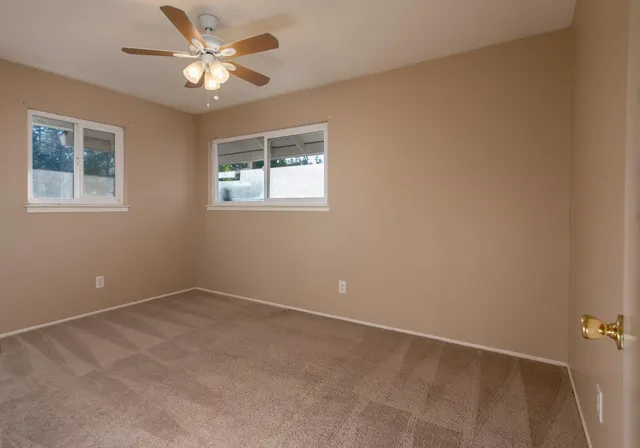 an empty room with a window and a fan