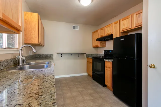 a kitchen with granite countertop a refrigerator and a sink