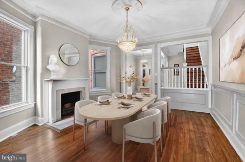 a dining room with wooden floor a chandelier a wooden table and chairs
