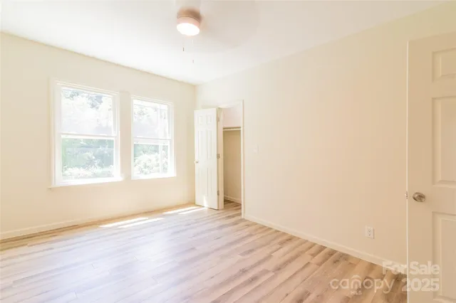 an empty room with wooden floor and windows