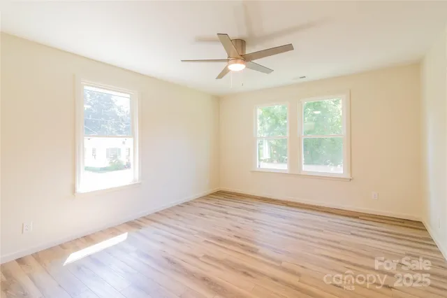 a view of an empty room with wooden floor and window