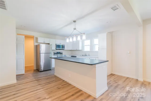 a kitchen with stainless steel appliances granite countertop a sink a stove a refrigerator and island with wooden floor