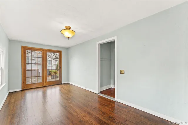 a view of an empty room with wooden floor and window