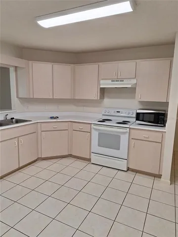 a white kitchen with cabinets stove top oven and sink