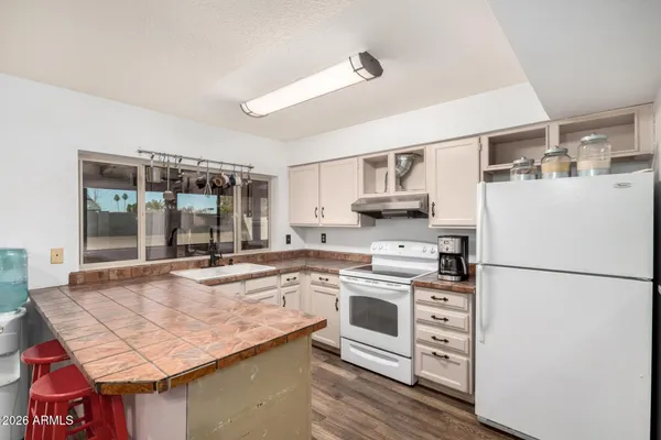 a kitchen with granite countertop a refrigerator a stove a sink and white cabinets