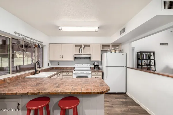 a kitchen with granite countertop a refrigerator a stove and white cabinets with wooden floor