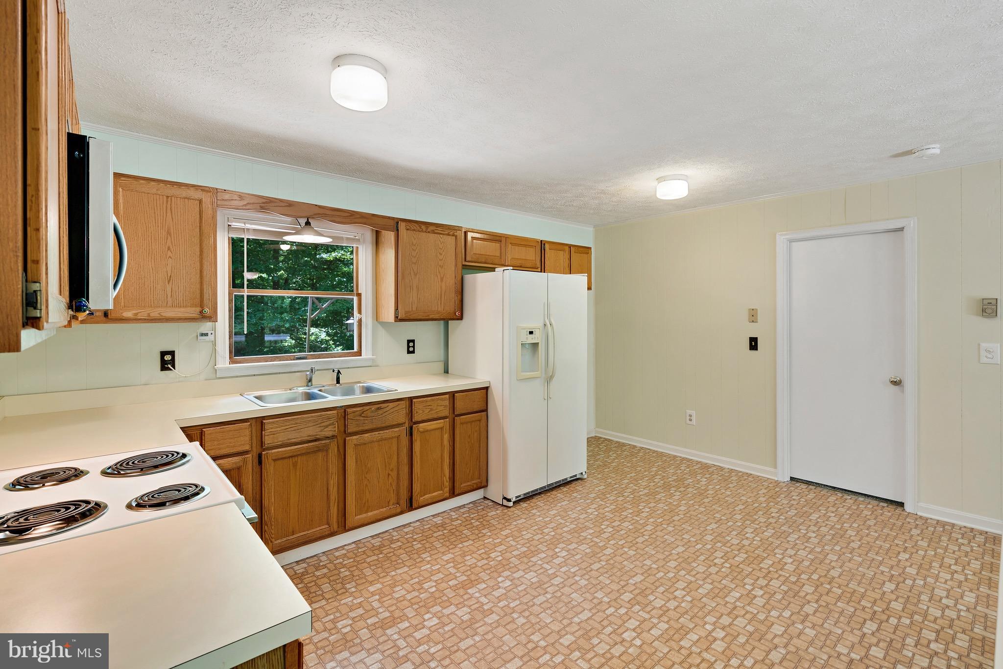 11320 Drogheda Mountain Road Rixeyville, VA 22737 - Photo 8 of 29 a kitchen with stainless steel appliances a sink a stove a refrigerator and cabinets