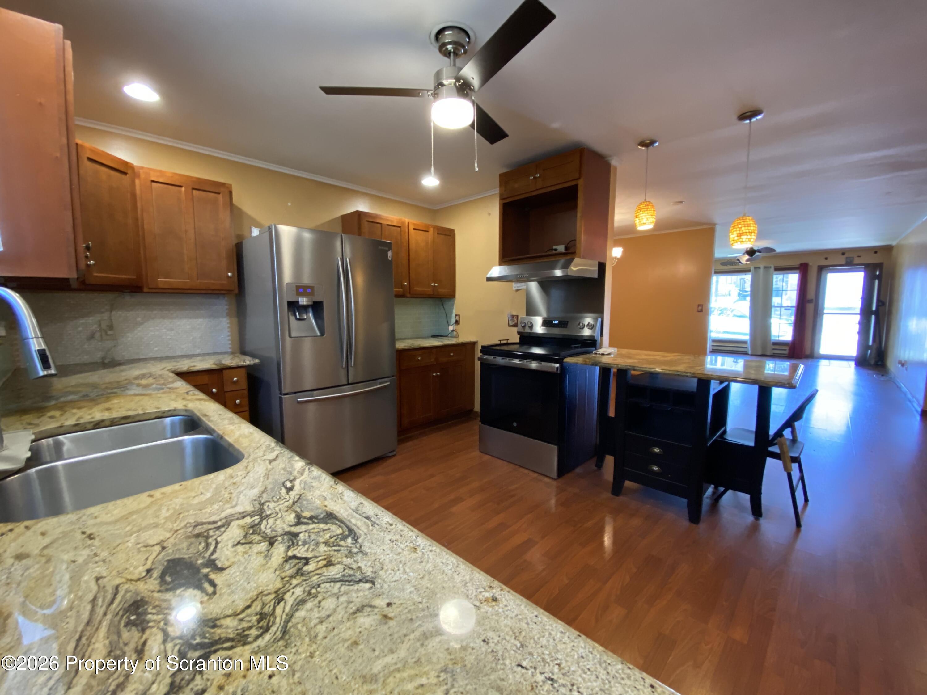 1019 Moosic Street Scranton, PA 18505 - Photo 13 of 43 a kitchen with stainless steel appliances kitchen island granite countertop a refrigerator a stove a sink a dining table and chairs with wooden floor