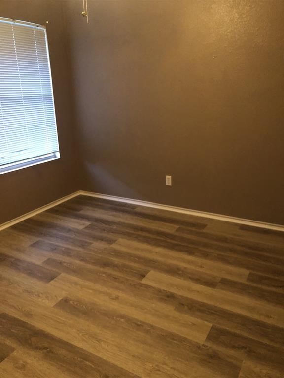 211 Woodley Road Leander, TX 78641 - Photo 9 of 15 Smooth wood-look flooring and crisp baseboards frame a versatile room with a large window.