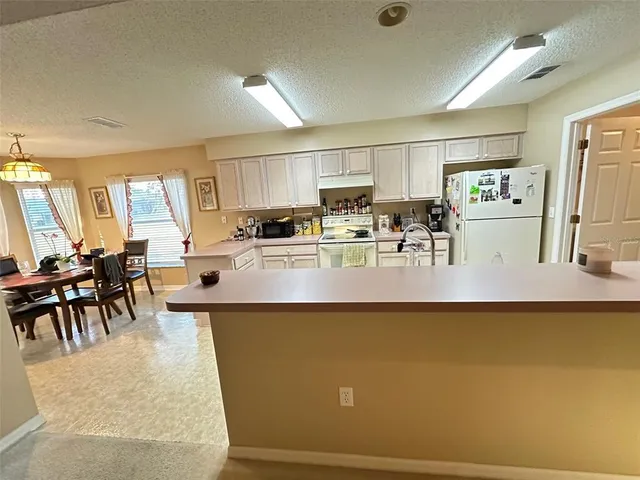 a living room with stainless steel appliances granite countertop furniture a refrigerator a kitchen island a stove and a sink