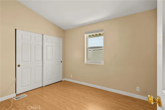 an empty room with wooden floor and bathroom view
