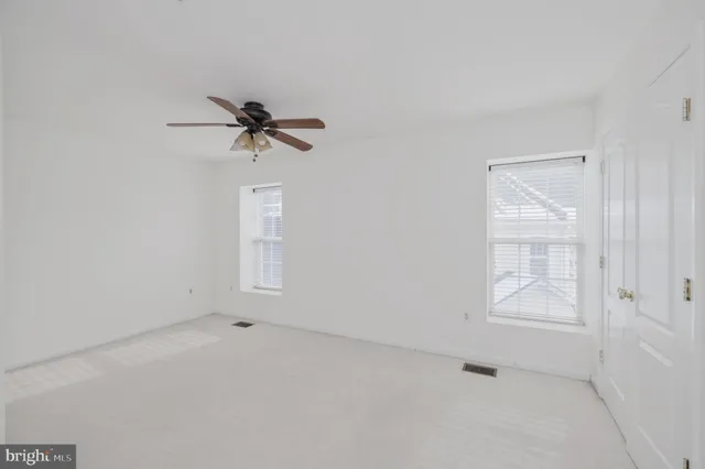 an empty room with a window and a ceiling fan