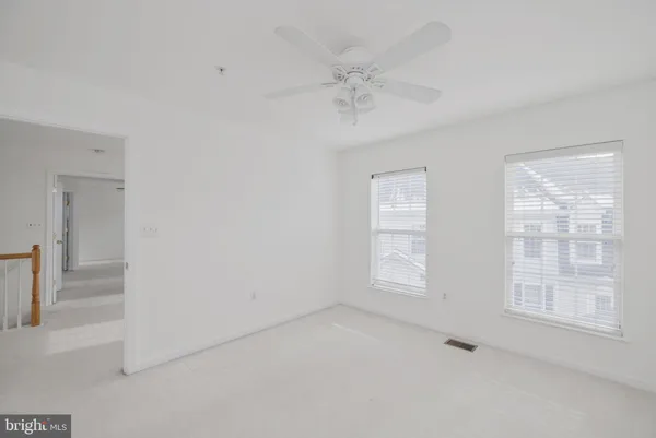 an empty room with windows and fan