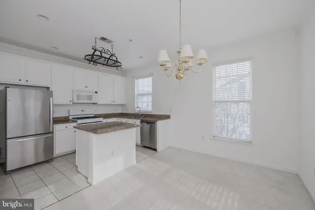 a kitchen with stainless steel appliances granite countertop a sink a stove a refrigerator cabinets and a window