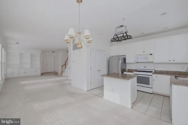 a kitchen that has a lot of white cabinets and stainless steel appliances