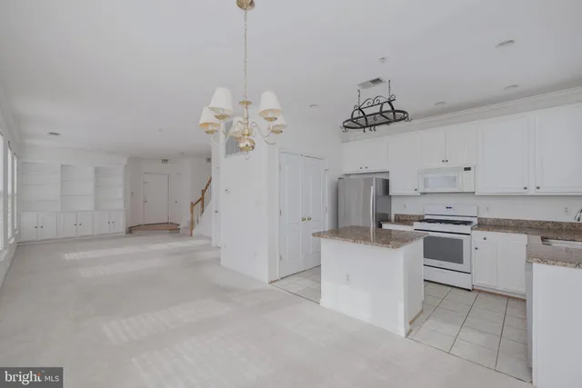 a kitchen that has a lot of white cabinets and stainless steel appliances