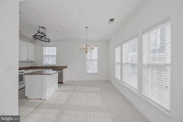 a kitchen with granite countertop a stove a sink and white cabinets