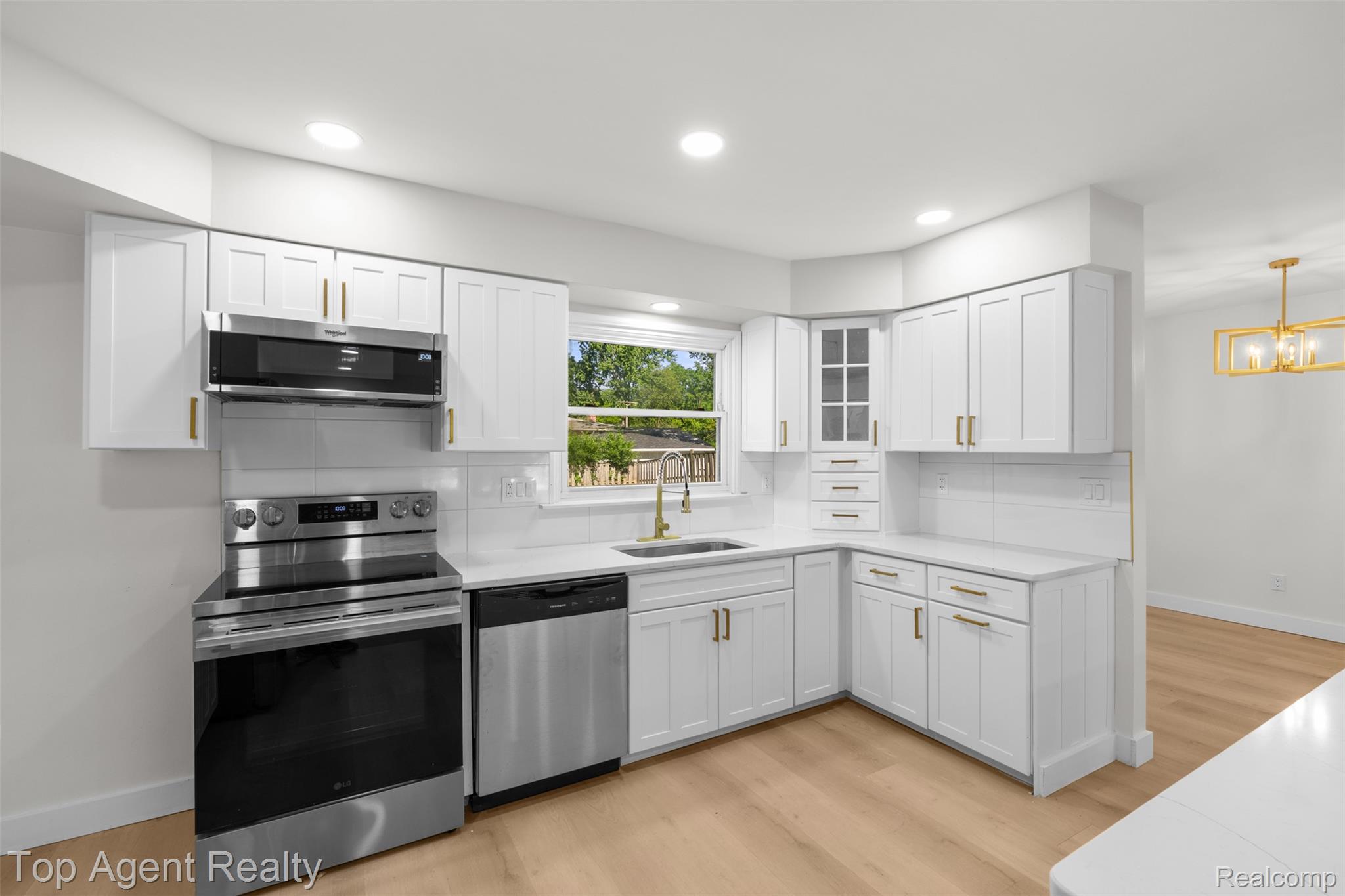 29863 Fall River Road Southfield, MI 48076 - Photo 7 of 50 Contemporary kitchen featuring white cabinetry, stainless steel appliances, light wood-finish flooring, recessed lighting, and a gold-tone chandelier in the adjacent space