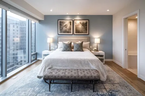 a bedroom with a bed mirror and a large window
