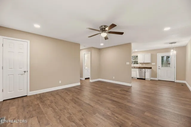 a view of an empty room with a kitchen and a window