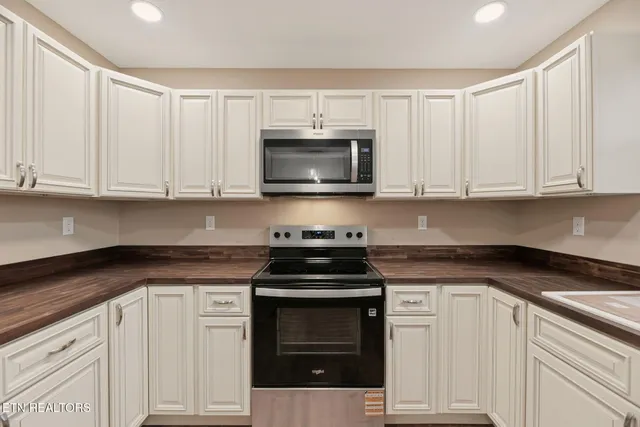 a kitchen with granite countertop white cabinets and stainless steel appliances