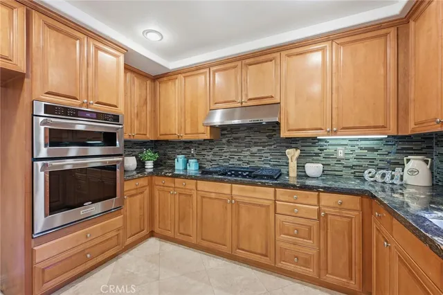 a kitchen with granite countertop a sink stainless steel appliances and cabinets