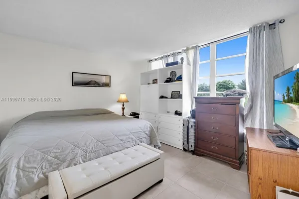 a bedroom with a bed dresser and a flat tv screen