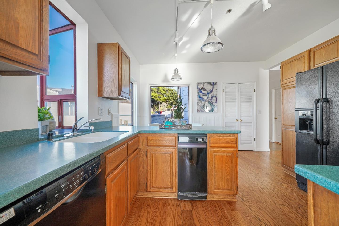 215 Roberts Road Pacifica, CA 94044 - Photo 11 of 40 a kitchen with stainless steel appliances granite countertop a refrigerator a sink dishwasher a stove and white countertops with wooden floor