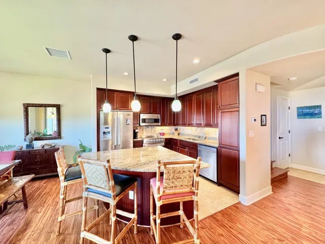 a kitchen with stainless steel appliances a dining table chairs and wooden floor