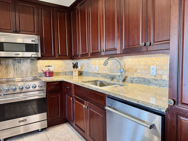 a kitchen with stainless steel appliances granite countertop wooden cabinets a stove and a sink