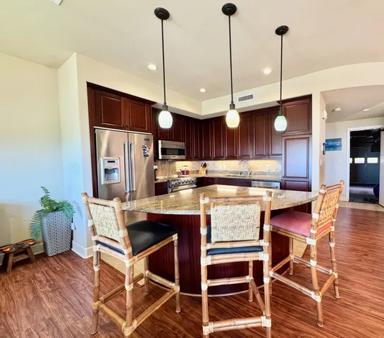 a kitchen with stainless steel appliances granite countertop a kitchen island a stove a table and chairs