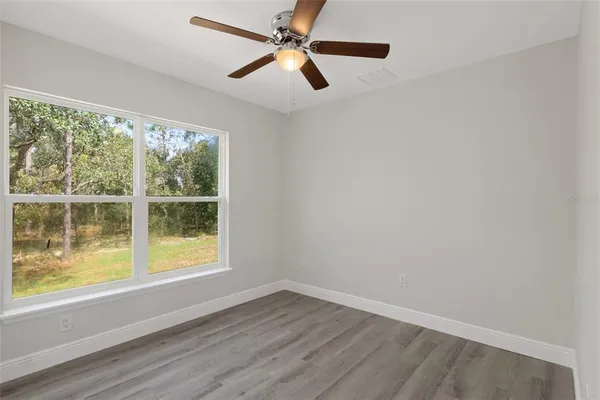 an empty room with wooden floor closet and windows