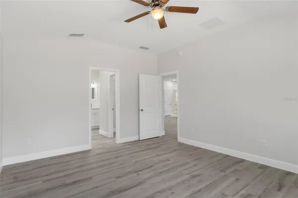 an empty room with wooden floor fan and windows