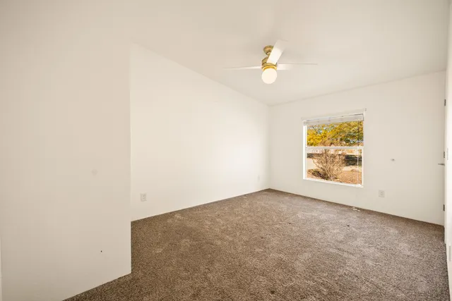 an empty room with a ceiling fan and a window