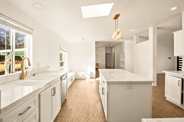 a large kitchen with granite countertop a sink dishwasher a stove and a dining table with a large window