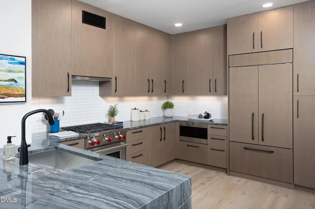 a kitchen with granite countertop a stove a sink and a refrigerator