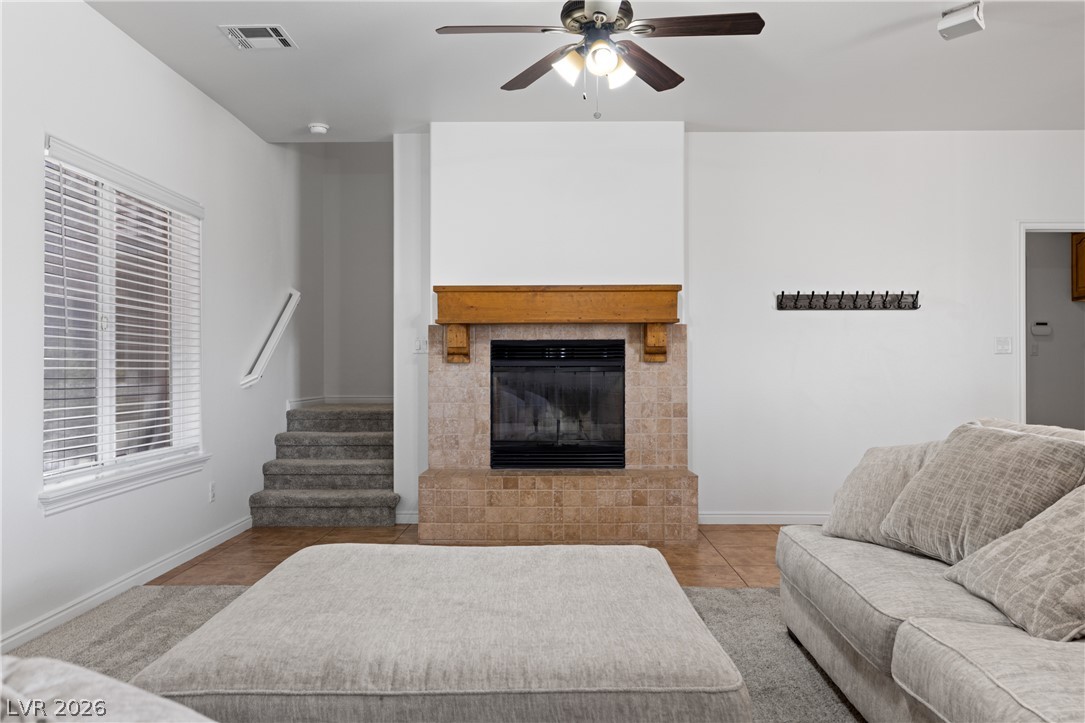 575 Gann Avenue Logandale, NV 89021 - Photo 14 of 75 An inviting living room, illuminated by natural light, features a tiled fireplace and staircase leading to upper levels.