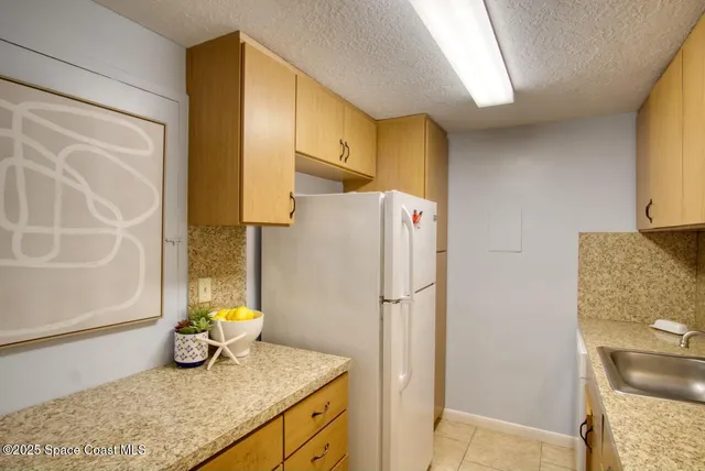 a bathroom with a granite countertop sink and a refrigerator